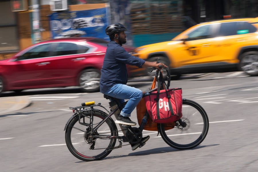 FILE - A delivery worker rides a motorized bicycle, July 25, 2023, in New York. On Monday, Nov. 13, New York City officials said that retailers and food delivery companies must do more to halt the proliferation of unsafe e-bike and e-scooter batteries after a fire blamed on an electric scooter's lithium ion battery killed three people over the weekend. (AP Photo/Seth Wenig, File)