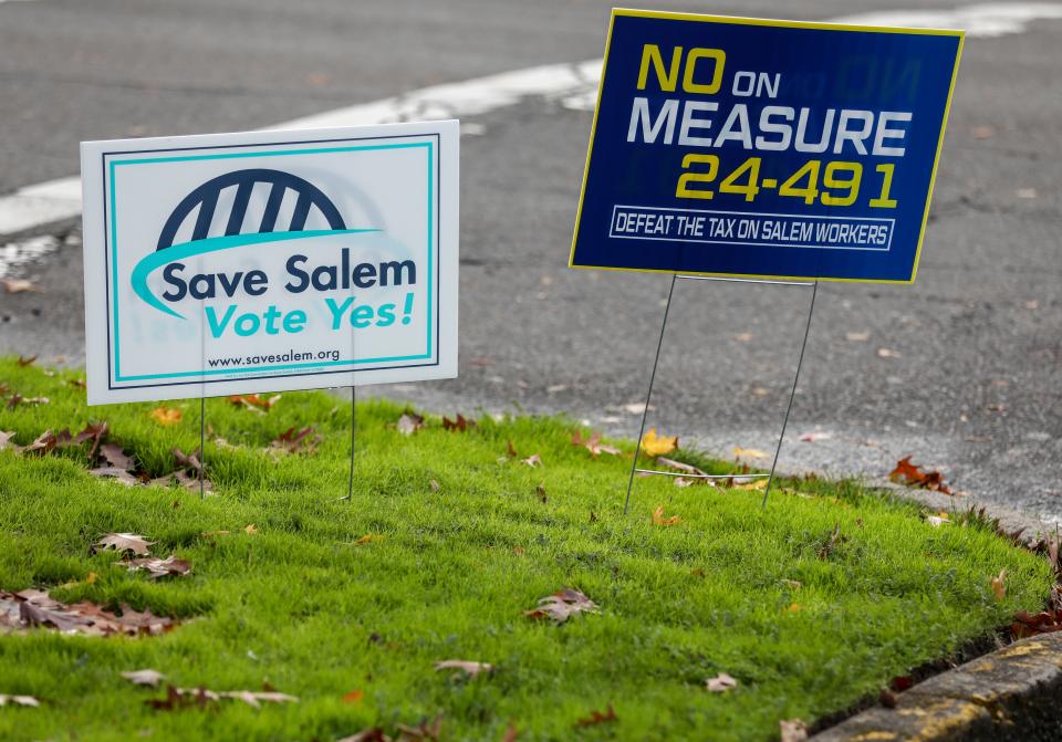 Signs in support of and against Salem's proposed payroll tax for public safety and social services staked near the Salem Saturday Market.