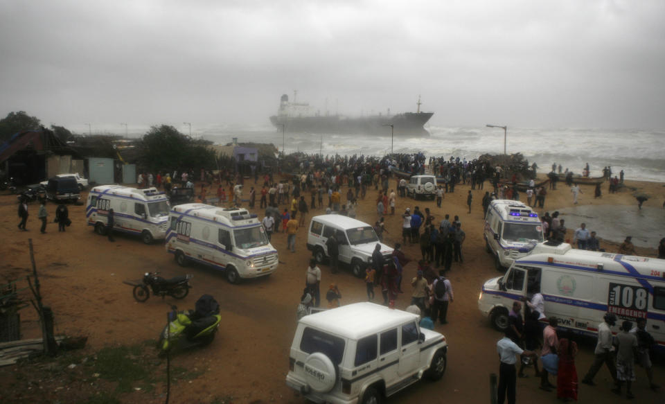 Ambulances stand on shore as people look at Indian ship Pratibha Cauvery that ran aground with people on board, reportedly due to strong winds on the Bay of Bengal coast in Chennai, India, Wednesday, Oct. 31, 2012. More than 100,000 people were evacuated from their homes Wednesday as a tropical storm hit southern India from the Bay of Bengal, officials said. Rain lashed the region and strong winds uprooted trees in some places. Weather officials said the storm packed winds of up to 100 kilometers (60 miles) per hour as it made landfall near Chennai, the capital of Tamil Nadu state. (AP Photo/Arun Sankar K)