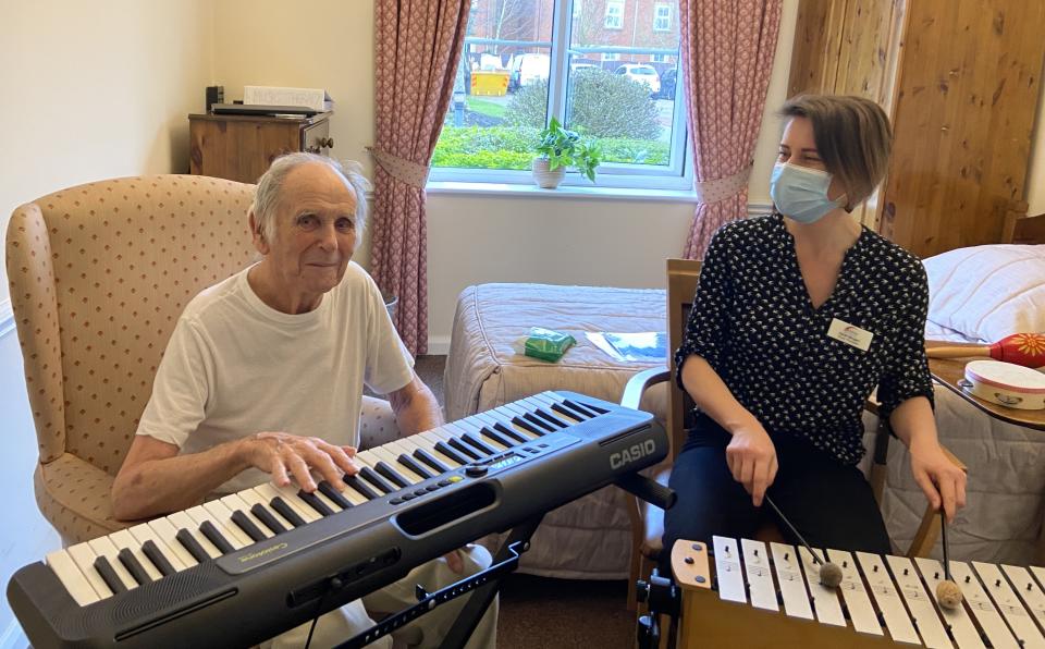 Man smiling at camera and playing keyboard