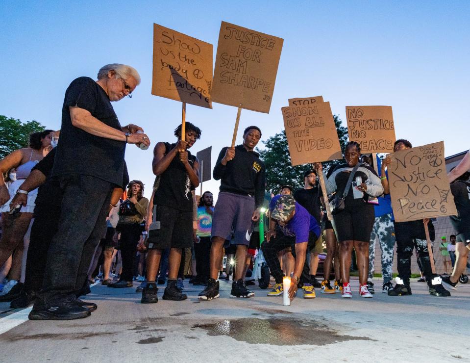 Mourners lay candles for Samuel Sharpe Jr. at the scene where he was shot on West Vliet Street as the Milwaukee Alliance Against Racist and Political Repression held a vigil for him on Tuesday at King Park in Milwaukee,