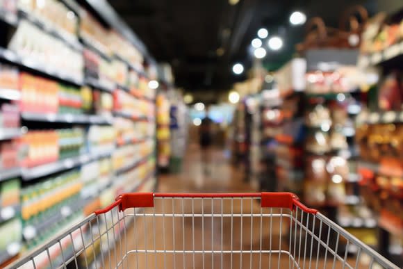 A grocery cart in a supermarket aisle.