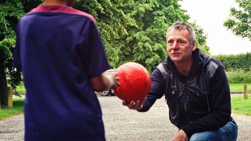 Stuart Pearce hands a red football to a boy wearing an England shirt