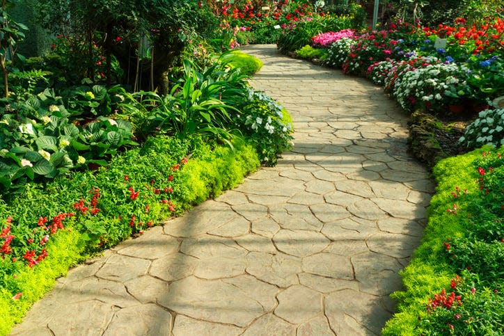 This stone walkway winds a path through a flower garden. Pavers are not a cheap project no matter where you buy bricks. But, put in properly, they last for years.