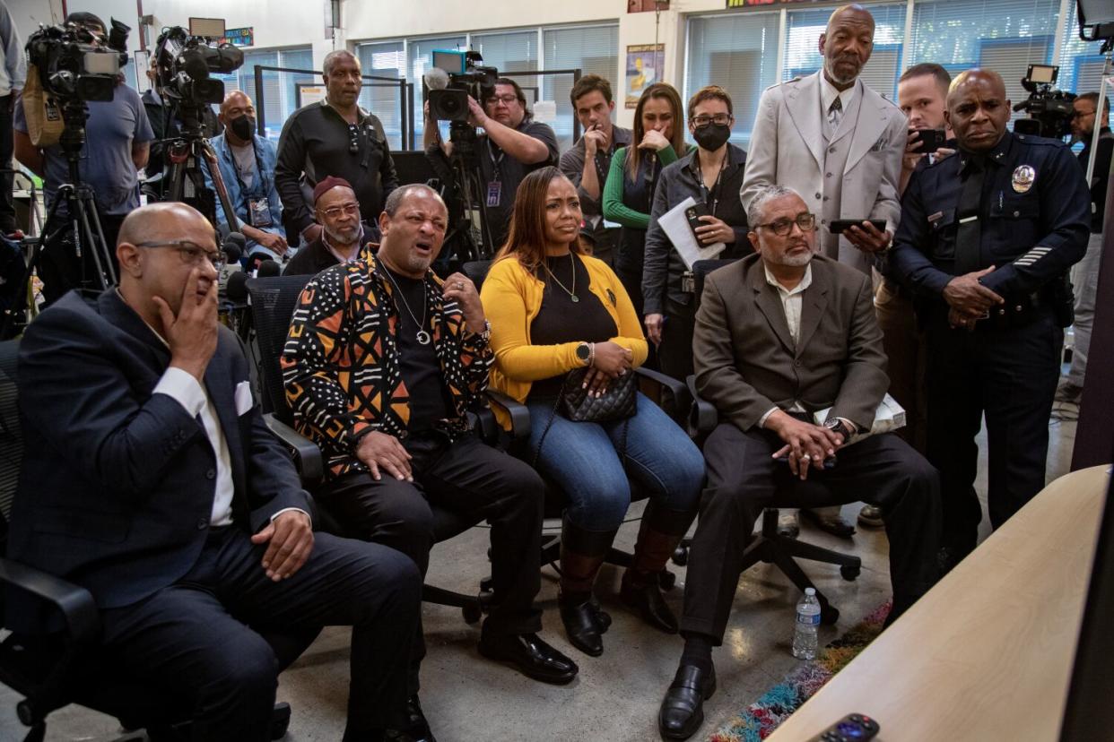 Television cameras filming a group of people as they watch a screen, appearing shocked