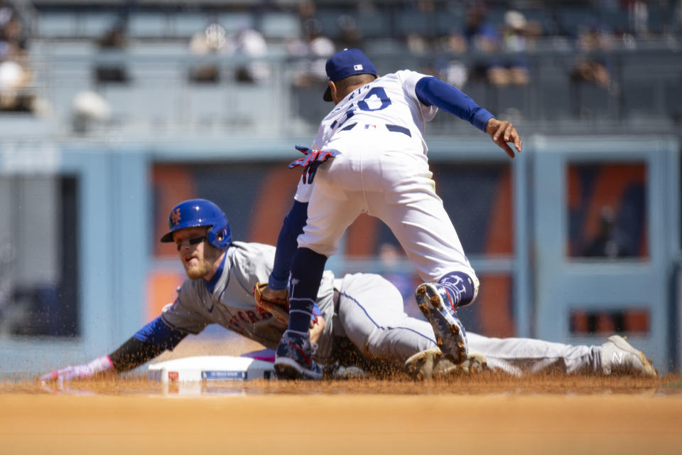 Los Angeles Dodgers shortstop Mookie Betts, right, tags out New York Mets' Harrison Bader who was trying to steal second base during the third inning of a baseball game in Los Angeles, Sunday, April 21, 2024. (AP Photo/Kyusung Gong)
