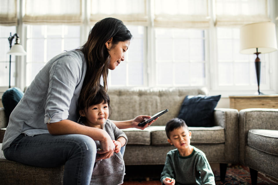 A woman looking at her phone while taking care of two children