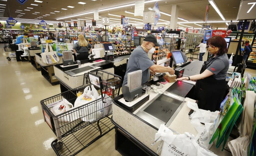 TORRANCE, CA - APRIL 27: Vons checker cashier Linda Poland has worked 27 years in this store as she works with customers at the Vons located at 24325 Crenshaw Blvd in Torrance. Doors to the store opened at 6 a.m. for seniors and at-risk shoppers due to the Coronavirus and at 7 a.m. for regular customers. Most of the team arrives at 5 a.m. to stock the shelves with product, sanitize the location for staff and shoppers, and picker/shoppers begin to collect items for .com home delivery shoppers. Vendors arriving throughout the morning must read a checklist of warnings, sign in and they must wear face covering. Vons on Monday, April 27, 2020 in Torrance, CA. (Al Seib / Los Angeles Times)