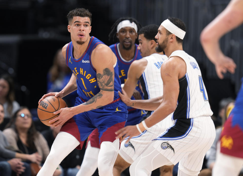 Denver Nuggets forward Michael Porter Jr., left, looks to pass the ball as Orlando Magic guard Jalen Suggs (4) defends in the first half of an NBA basketball game Friday, Jan. 5, 2024, in Denver. (AP Photo/David Zalubowski)