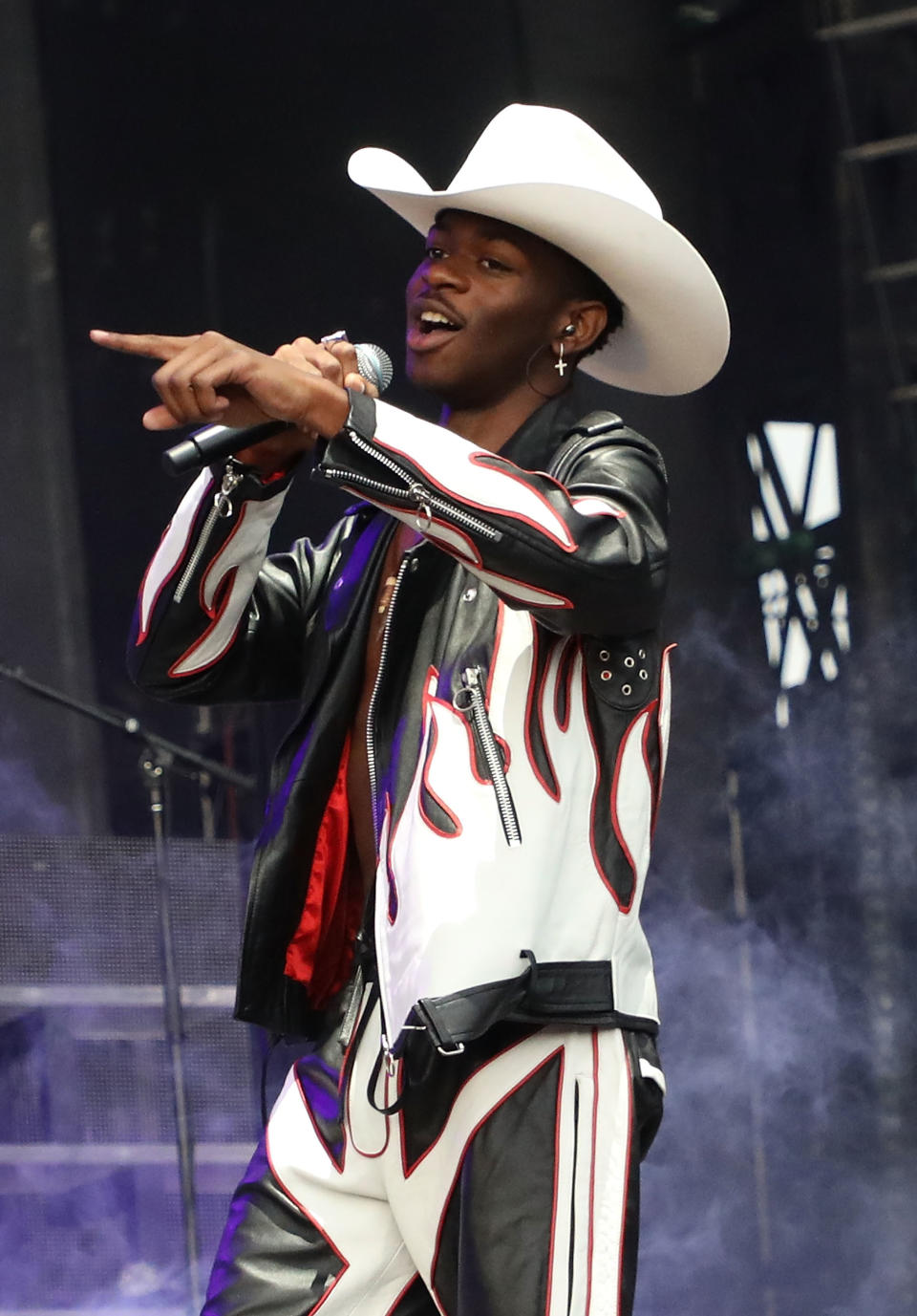 Lil Nas X performs on stage wearing a cowboy hat and a leather outfit with flame designs