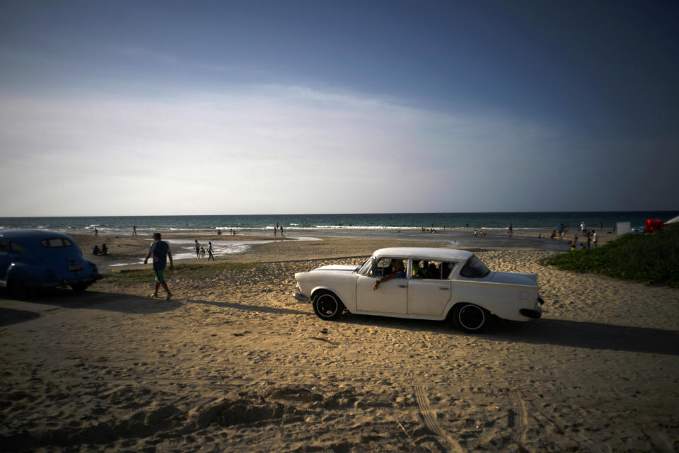 FILE-In this July 18, 2019 file photo afamily arrives on the beach in a classic American car on the outskirts of Havana, Cuba. Scientists say that half of the world's sandy beached are at risk of disappearing by the end of the century if climate changes continues unchecked. Researchers at the European Union's Joint Research Center in Ispra, Italy, used satellite images to track the way beaches changed over the past 30 years and project how global warming might affect them in the future. (AP Photo/Ramon Espinosa)