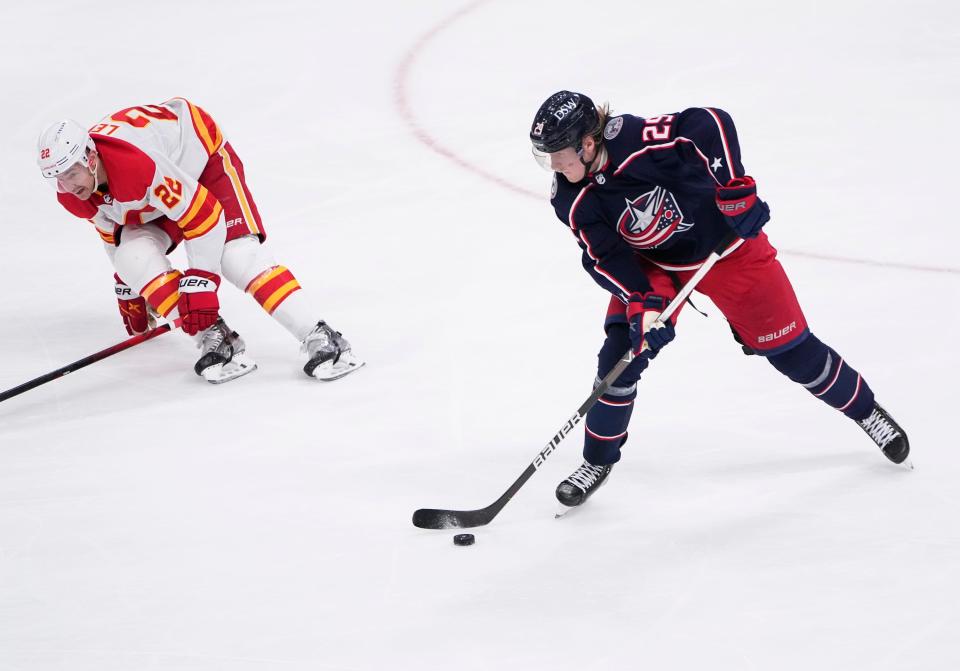 Columbus Blue Jackets left wing Patrik Laine (29) skates around Calgary Flames center Trevor Lewis (22) during the second period of the NHL hockey game at Nationwide Arena in Columbus on Wednesday, Jan. 26, 2022. 