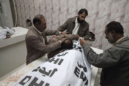 A man (2nd L) mourns over the covered body of his brother who was among four workers of an anti-polio drive campaign shot by gunmen, at a hospital morgue in Quetta November 26, 2014. Gunmen killed three Pakistani women polio workers and their driver on Wednesday, police said, in the most deadly attack on the health workers in two years. REUTERS/Naseer Ahmed