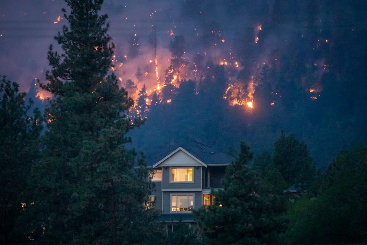 A wildfire burns near a home in the city of Kelowna, B.C., on Aug. 18, 2023.  (Ben Nelms/CBC - image credit)