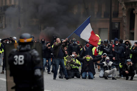 A protester waves a French flag during clashes with police at a demonstration by the "yellow vests" movement in Paris, France, December 8, 2018. REUTERS/Benoit Tessier