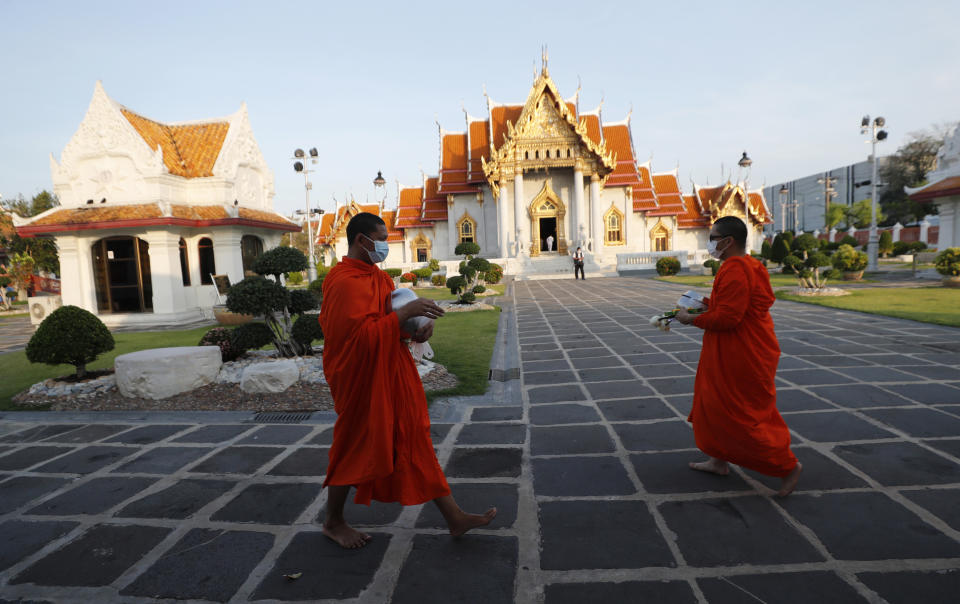 Buddhist monks wear face masks to protect themselves from the coronavirus during a morning alms offerings at Marble Temple in Bangkok, Thailand Friday, April 16, 2021. (AP Photo/Sakchai Lalit)