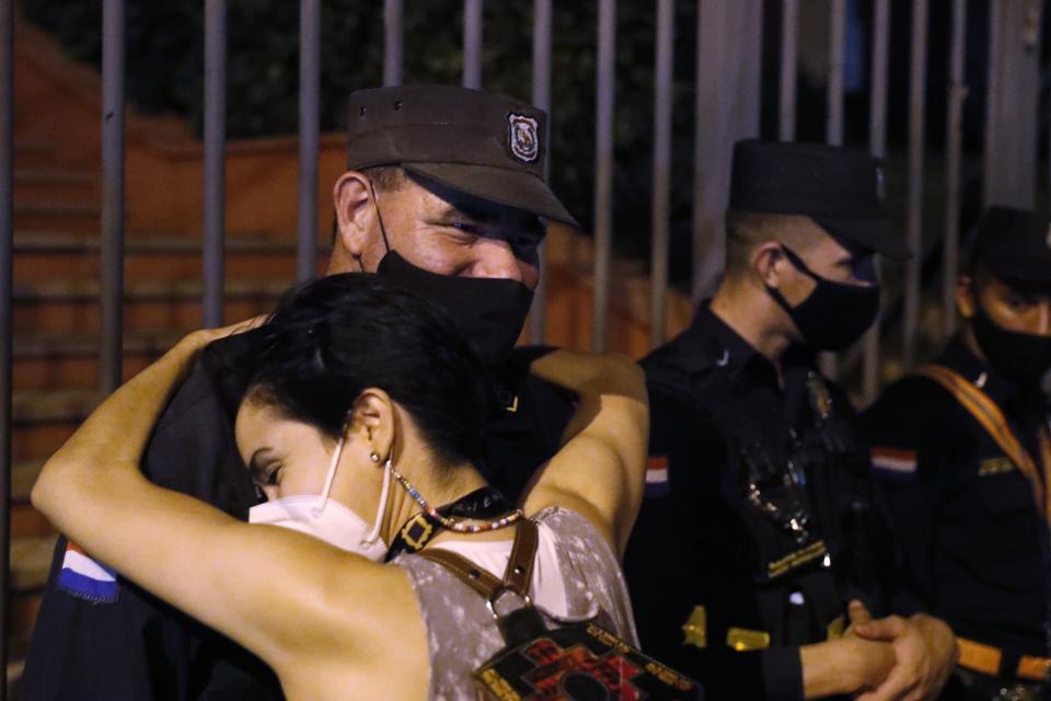 A woman embraces a police officer as people protest, calling for the resignation of President Mario Abdo Benitez over his handling of the coronavirus pandemic and the state of the public health system, in Asuncion, Paraguay, Monday, March 8, 2021. (AP Photo/Jorge Saenz)