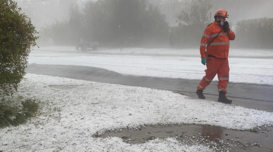 A SES worker walks down a street blanketed in hail. Source: NSW SES/Twitter