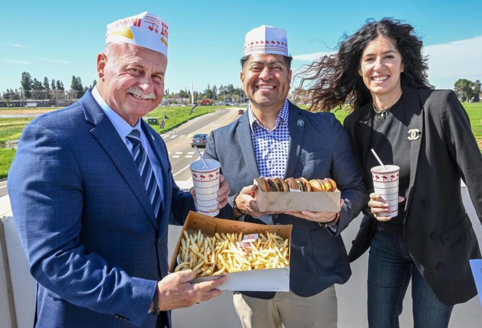 Fresno Mayor Jerry Dyer, Councilmember Luis Chavez and Tracy Kashian, vice president of marketing/public relations at Lance-Kashian & Co. hold In-N-Out Burger food and drinks while announcing future tenants of the new Fancher Creek Town Center while standing atop the center’s parking garage. An In-N-Out drive-thru is one of them.