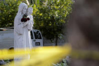 A religious statue sits beyond yellow tape roping off a closed public park during the coronavirus pandemic, Thursday, April 9, 2020, in Miami. Religious leaders worldwide are urging people to celebrate Good Friday and Easter from the safety of their homes. (AP Photo/Lynne Sladky)