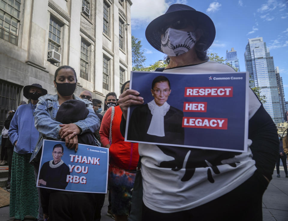 People hold signs of tribute during a public remembrance to honor the life and legacy of U.S. Supreme Court Justice and former Brooklynite Ruth Bader Ginsburg, outside Brooklyn's, Municipal Building, Sunday Sept. 20, 2020, in New York. Brooklyn Borough President Eric Adams is calling on Mayor Bill de Blasio to rename the Municipal Building in honor of Justice Ginsburg, a Brooklynite who passed away Friday at the age of 87. (AP Photo/Bebeto Matthews)