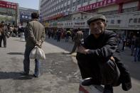 A man squats on a concrete barrier as others wash and scrub the site of the Wednesday explosion outside the Urumqi South Railway Station in Urumqi in northwest China's Xinjiang Uygur Autonomous Region on Thursday, May 1, 2014. Chinese President Xi Jinping demanded “decisive” action against terrorism after a slashing and bomb attack at a Xinjiang train station killed three people and injured 79 while the leader was wrapping up a tour of the far-western region.(AP Photo/Ng Han Guan)