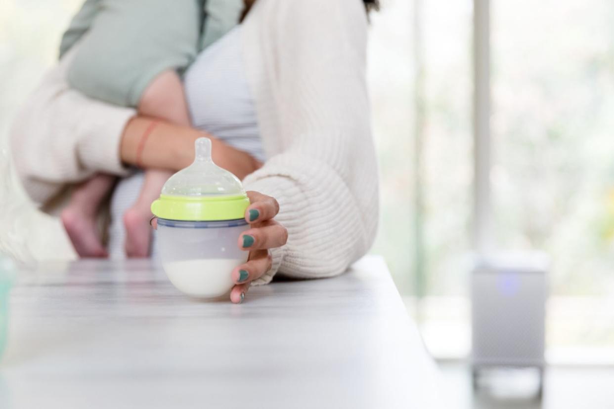 An image of a mom grabbing a bottle for her baby.