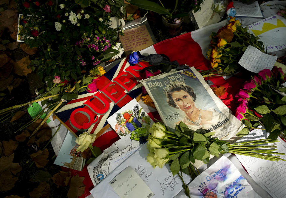 Photos and flowers are shown people pay their respects near the gates of Buckingham Palace in London on Sunday, Sept. 11, 2022. (Nathan Denette/The Canadian Press via AP)