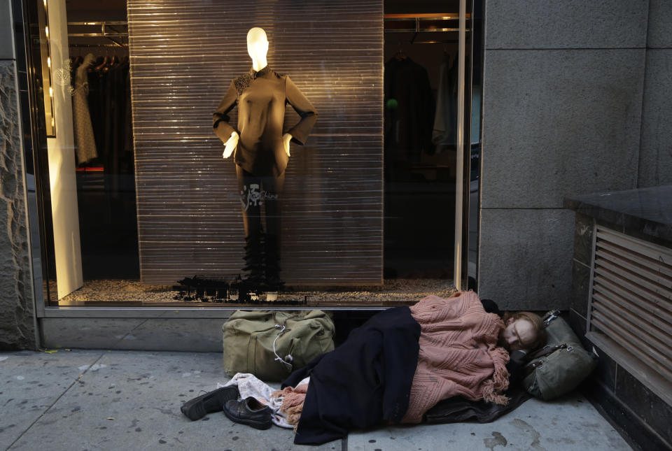 FILE - In this Wednesday, Nov. 20, 2013, file photo, a destitute man sleeps on the sidewalk under a holiday window at Blanc de Chine, in New York. A Gallup poll found two-thirds of Americans are dissatisfied with the nation’s distribution of wealth. (AP Photo/Mark Lennihan, File)