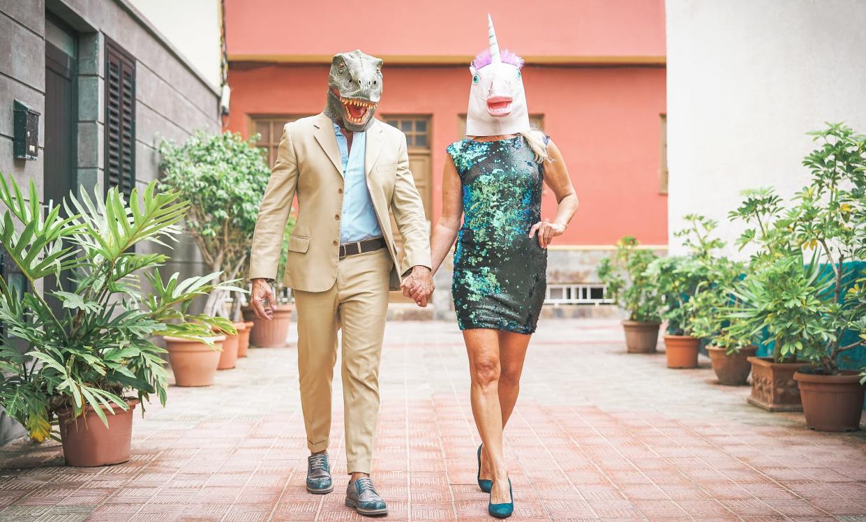 Cuple wearing dinosaur and unicorn masks.