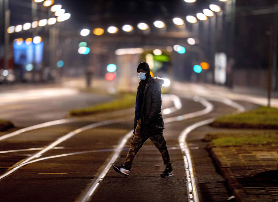 A man wearing a face mask crosses railroad tracks near a tram station in Frankfurt, Germany, early Sunday, Dec. 26, 2021. (Photo/Michael Probst)