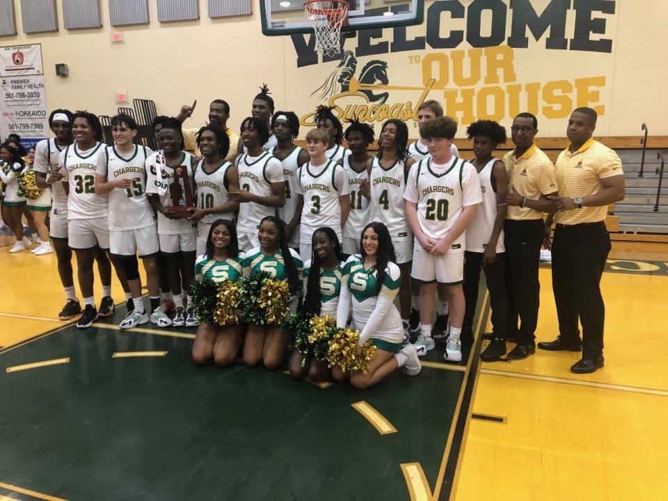 Coach Jason Powell (right) and the Suncoast Chargers pose with the District 14-5A trophy after beating Fort Lauderdale-Stranahan on Friday night in Riviera Beach.