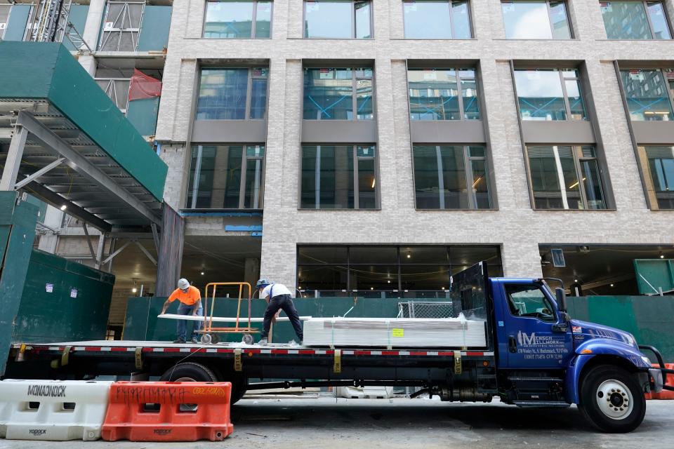 Construction workers unload sheet rock at a residential and commercial building under construction at the Essex Crossing development on the Lower East Side of Manhattan on Aug. 4, 2022.  America’s hiring boom continued last month as employers added a surprising 528,000 jobs despite raging inflation and rising anxiety about a recession.