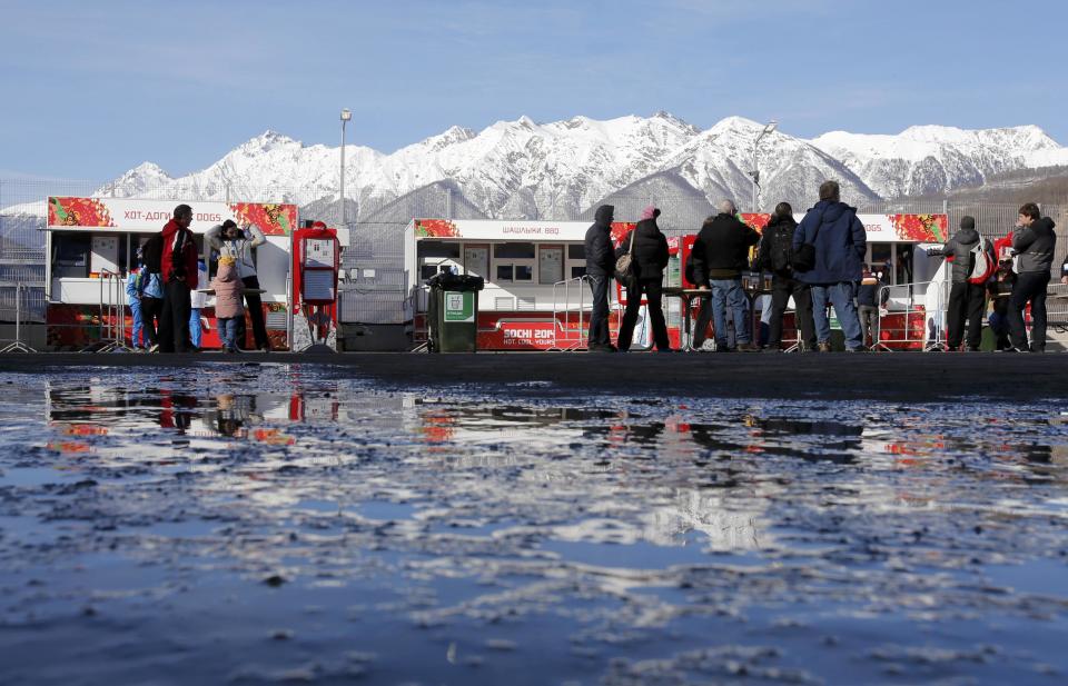 People stand near food stalls on a sunny day at the Sanki Sliding Center in Rosa Khutor, a venue for the Sochi 2014 Winter Olympics near Sochi, February 12, 2014. REUTERS/Fabrizio Bensch