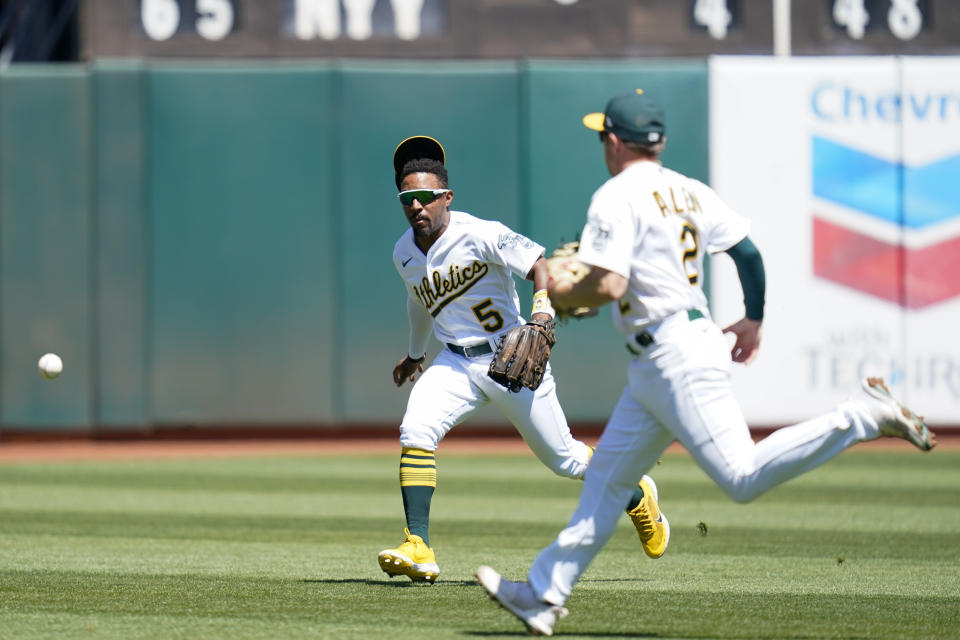 Oakland Athletics left fielder Tony Kemp (5) and shortstop Nick Allen (2) are unable to catch a fly ball hit by Seattle Mariners' Dylan Moore who singled during the second inning of a baseball game in Oakland, Calif., Sunday, Aug. 21, 2022. (AP Photo/Godofredo A. Vásquez)