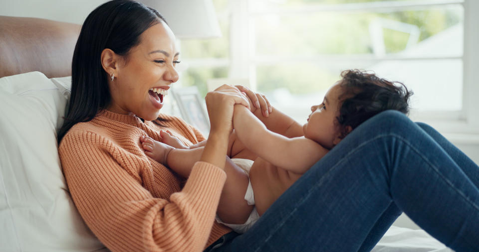 a woman sitting down and playing with a baby on her legs