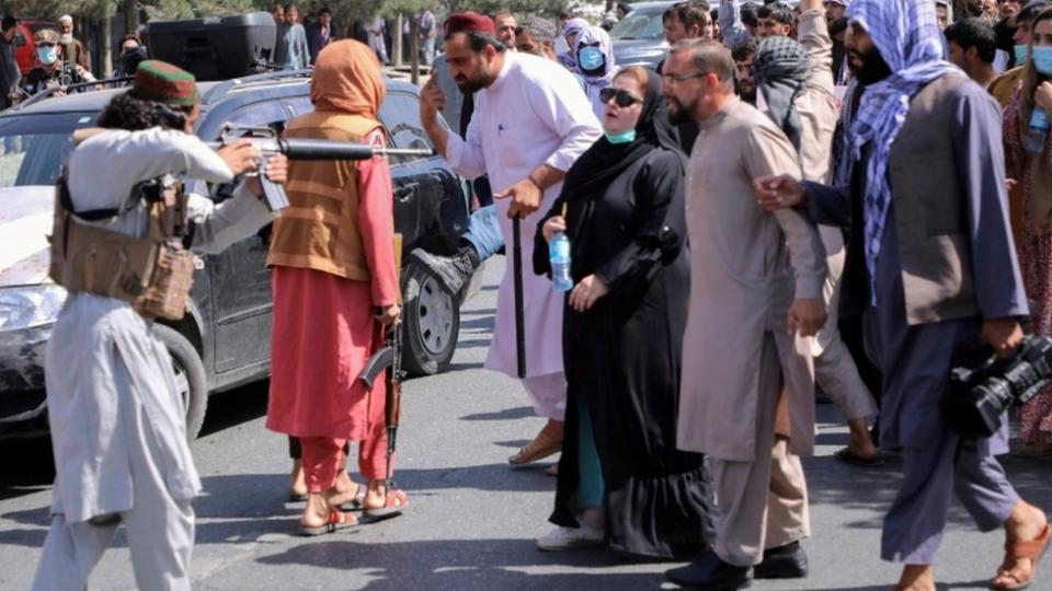 A Taliban fighter points a gun at a woman during a demonstration in Kabul