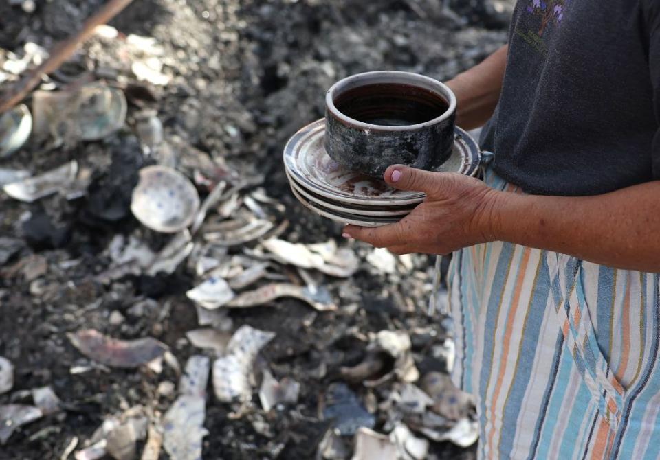 A resident found some dishes among the rubble of a  house that survived the wildfire.