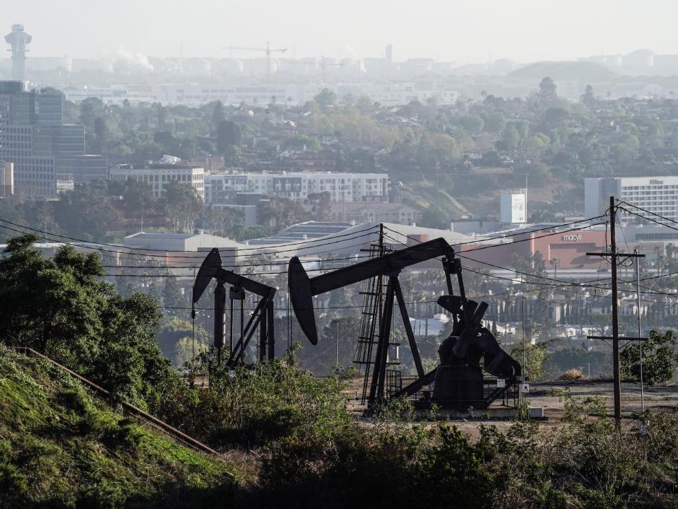 black pumpjacks for oil wells beside dense housing in california