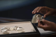 Isaac Levy, owner of Israeli jewelry company Yvel holds parts of a mask in Motza near Jerusalem, Sunday, Aug. 9, 2020. An Israeli jewelry company is working on what it says will be the world's most expensive coronavirus mask, a gold, diamond-encrusted face covering with a price tag of $1. 5 million. (AP Photo/Sebastian Scheiner)