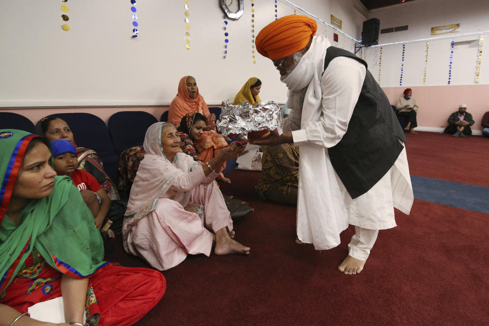 ***HOLD FOR RELIGION TEAM STORY*** Priest (Bhai) Ram Singh hands out sweet treats to the faithful during the Shri Guru Ravidass Sabha ceremony at a temple in Fresno, Calif. Sunday, May 7, 2023. Members of the Ravidassia community in California are followers of Guru Ravidass, a 14th century Indian guru of a caste formerly considered untouchable. The Ravidassia community statewide is advocating for new legislation to outlaw caste-based discrimination. (AP Photo/Gary Kazanjian)