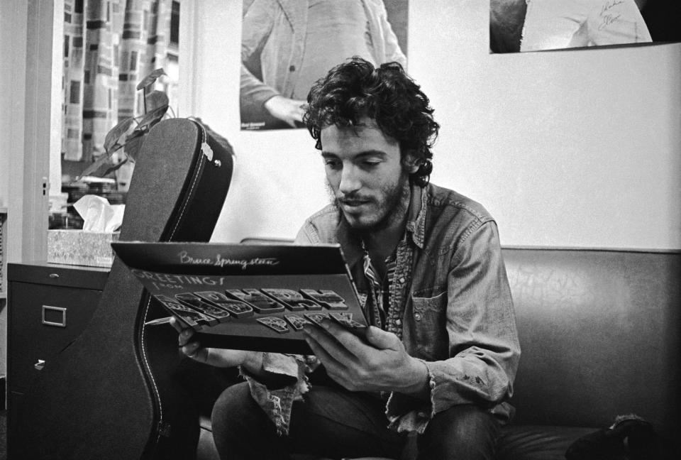 Bruce Springsteen shown in 1973, with a copy of "Greetings from Asbury Park, N.J."