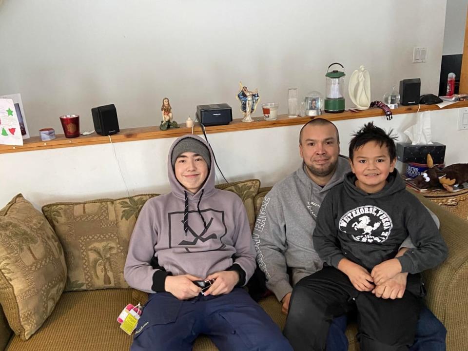 Ryan Gleeson of Whitehorse sits with his sons Brayden Gleeson and Joshua Gleeson-Blackjack. All 3 of them are playing this week in the Yukon Native Hockey Tournament. (Submitted by Ryan Gleeson - image credit)