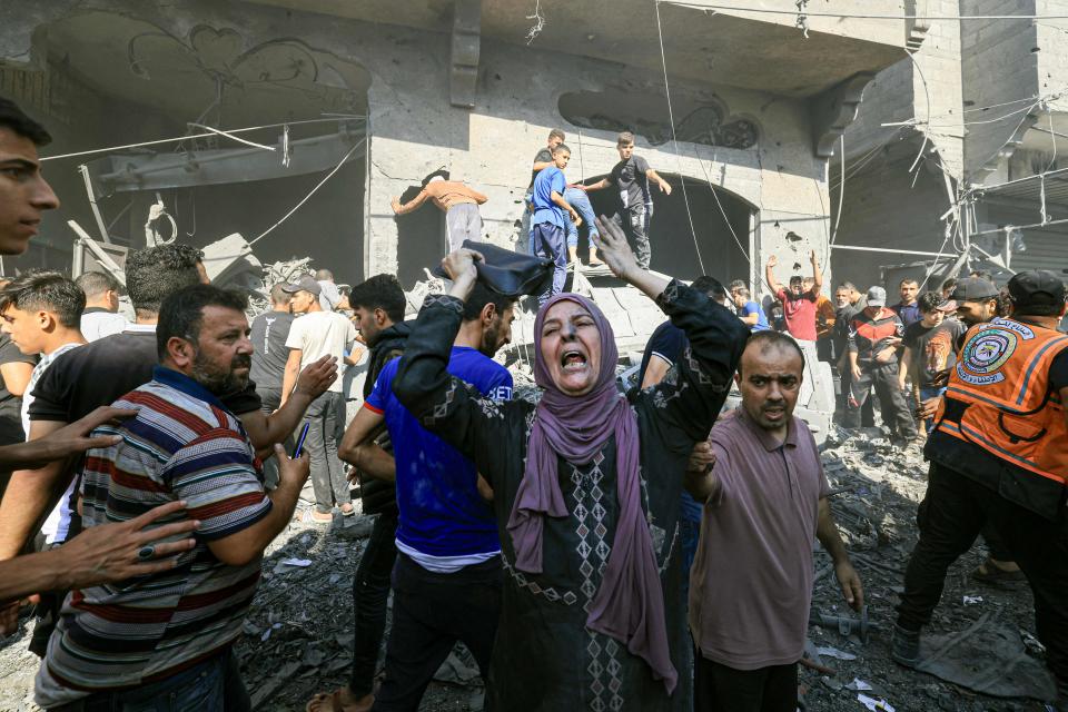 A Palestinian woman reacts as others rush to look for victims in the rubble of a building following an Israeli strike in Khan Yunis in the southern Gaza Strip on Oct. 17, 2023, amid the ongoing battles between Israel and the Palestinian group Hamas.