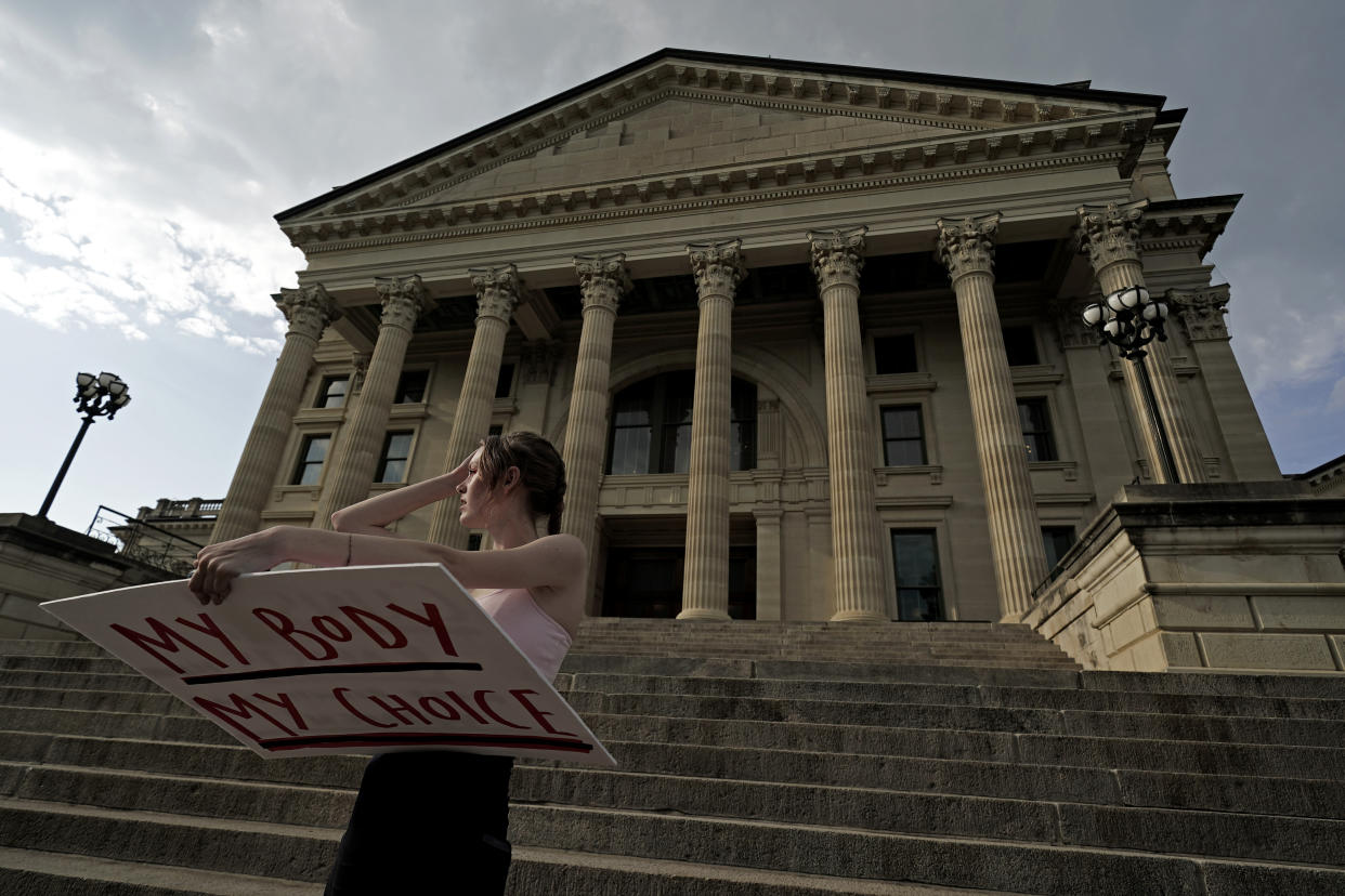 Zoe Schell stands on the steps of the Kansas Statehouse holding a sign saying: My Body, My Choice.