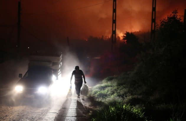 A man fleeing wildfires in Santa Olga, Chile, carries his belongings by the side of the road. Chile is currently experiencing the <a href="https://www.theatlantic.com/liveblogs/2017/01/news-today/514490/14201/" rel="nofollow noopener" target="_blank" data-ylk="slk:worst wildfires;elm:context_link;itc:0;sec:content-canvas" class="link ">worst wildfires</a> of its modern history. <a href="https://www.theatlantic.com/photo/2017/01/worst-wildfires-in-chiles-history/514583/" rel="nofollow noopener" target="_blank" data-ylk="slk:More photos here;elm:context_link;itc:0;sec:content-canvas" class="link ">More photos here</a>. (Pablo Sanhueza / Reuters)