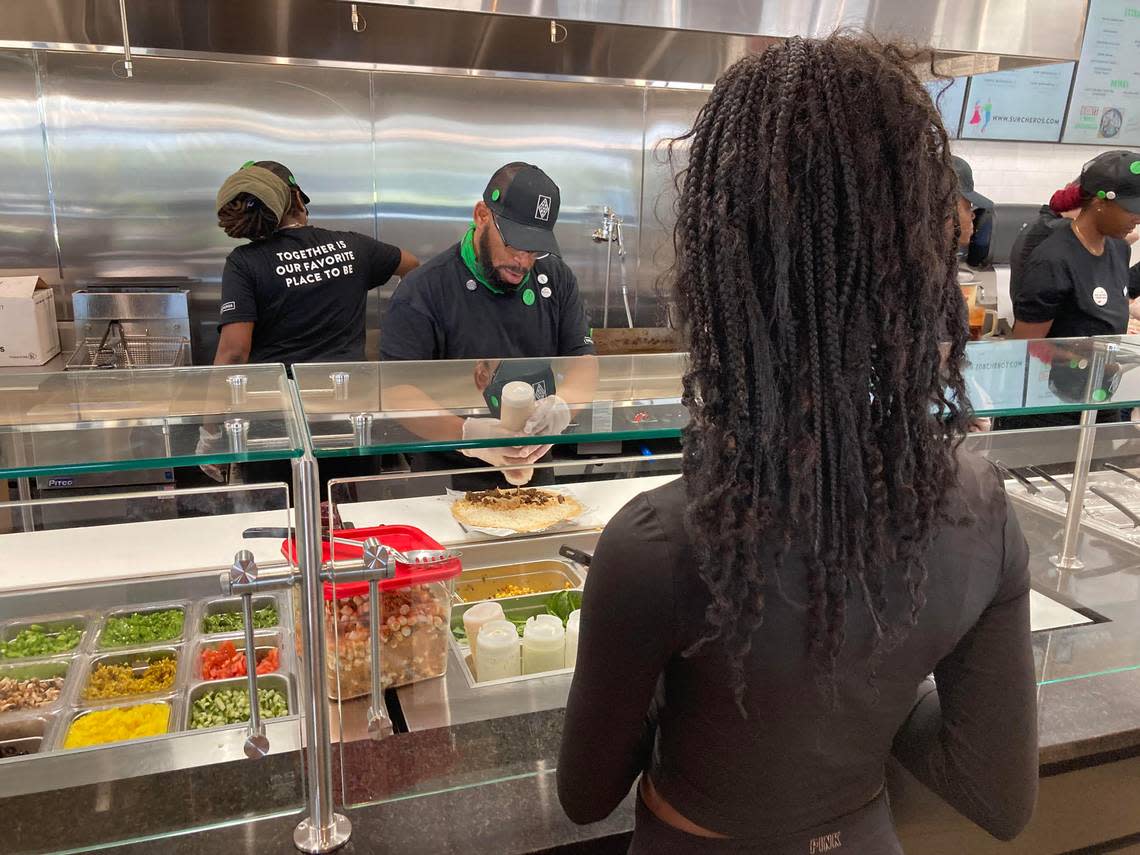 Ariana Jones of Warner Robins watches as her burrito is made-to-order at the new Surcheros Fresh Mex in Warner Robins at a friends and family event prior to the new restaurant’s opening. Jones works at the restaurant.