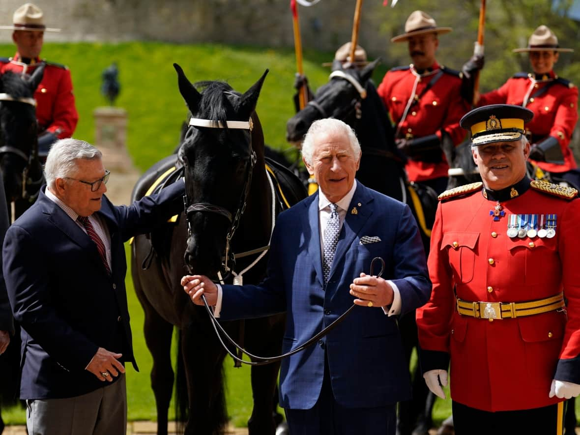 King Charles, centre, stands alongside High Commissioner for Canada in the U.K. Ralph Goodale (left) and RCMP Commissioner Mike Duheme after being officially presented with 'Noble', a horse given to him by the Royal Canadian Mounted Police earlier this year, as he formally accepted the role of commissioner-in-chief of the RCMP during a ceremony outside Windsor Castle on April 28, 2023. (Andrew Matthews/Pool via AP Photo - image credit)