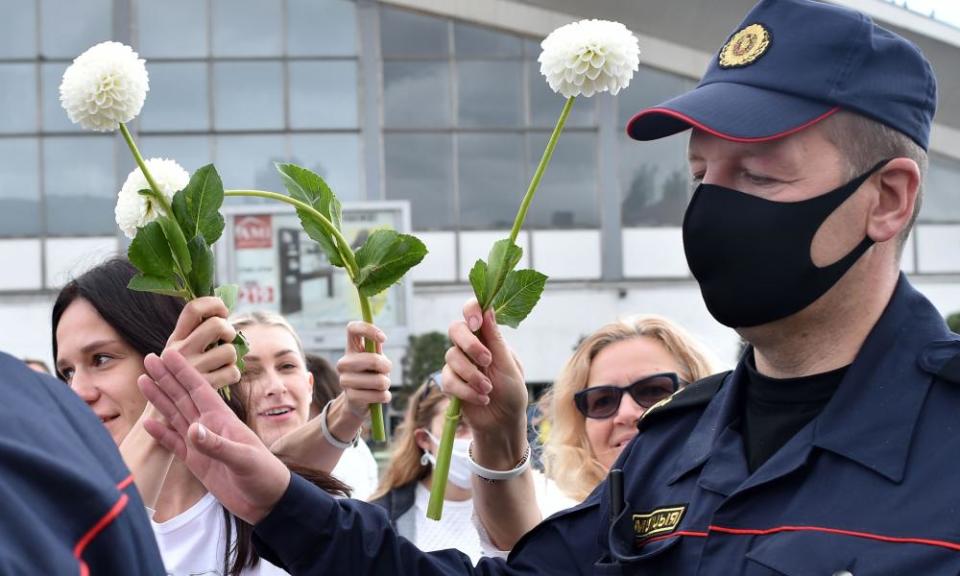 Women protesters offer flowers to police officers during a demonstration.