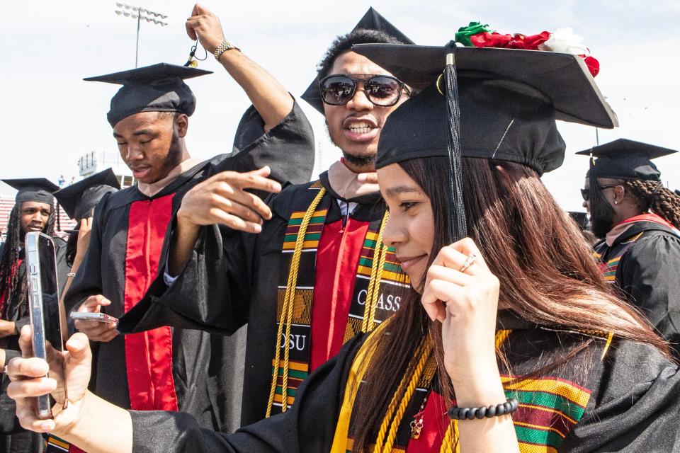 A graduate streams on social media as she turns her tassel during the Delaware State University 2023 commencement ceremony at Alumni Stadium in Dover, Friday, May 12, 2023.